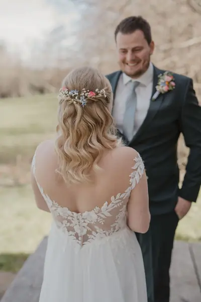 Halboffene blonde Brautfrisur mit Blumenkranz beim First Look